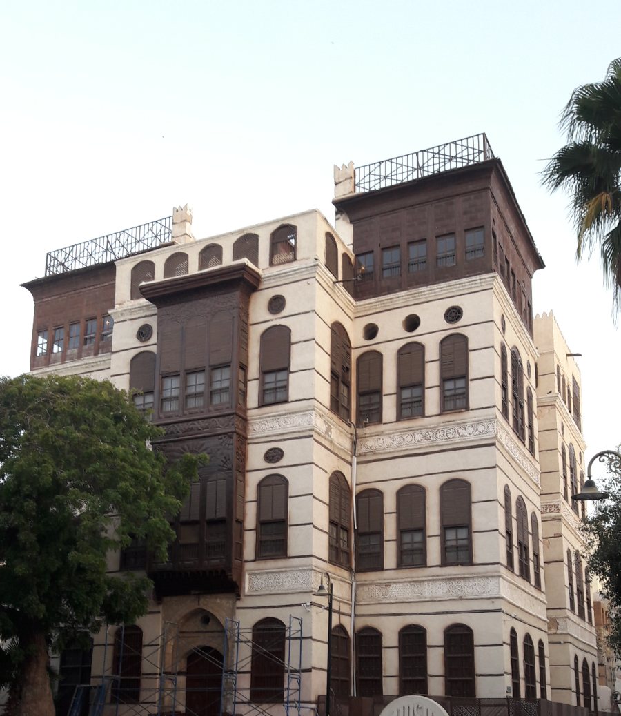 Bayt Nasseef in daylight — coral-plaster facade and dark timber rawashin above Suq al-Alawi
